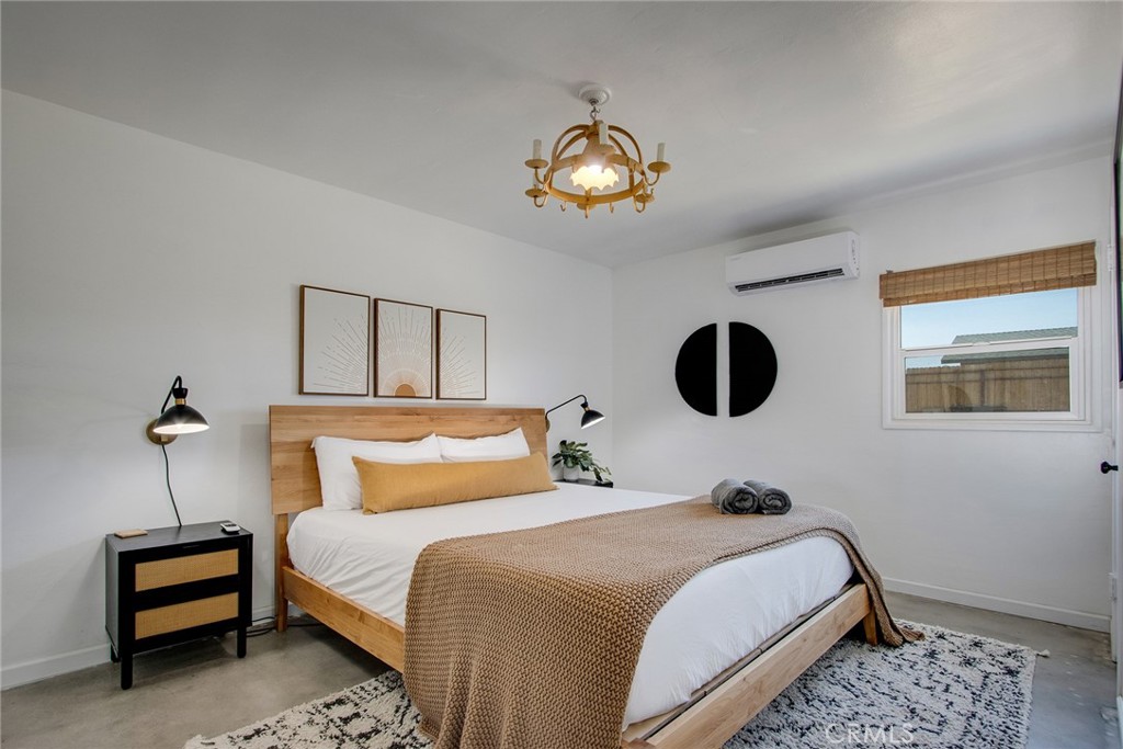 64975 Sun Oro Road Joshua Tree, CA 92252 - Photo 24 of 52 a bedroom with a bed and a chandelier