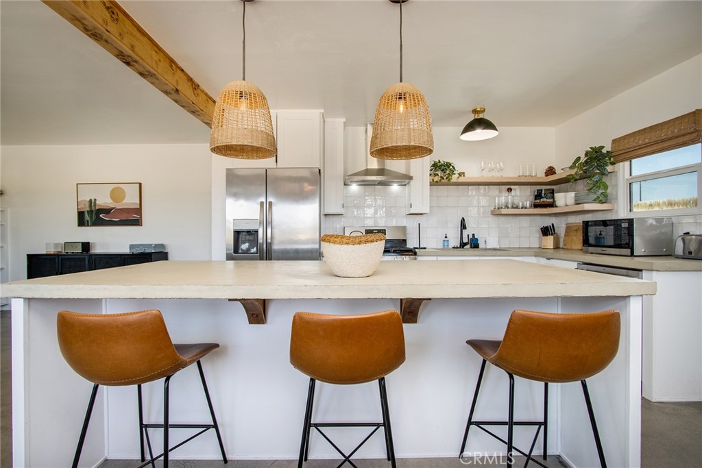 64975 Sun Oro Road Joshua Tree, CA 92252 - Photo 5 of 52 a kitchen with stainless steel appliances a dining table chairs and a refrigerator
