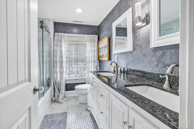 a spacious bathroom with a double vanity sink a mirror a bathtub and next to a window