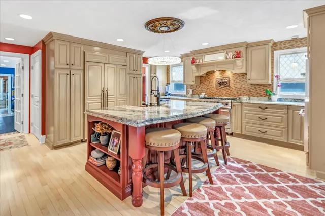 a dining hall with stainless steel appliances granite countertop a stove a sink a dining table and chairs with wooden floor