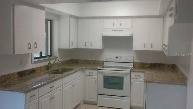 a kitchen with granite countertop white cabinets and white appliances