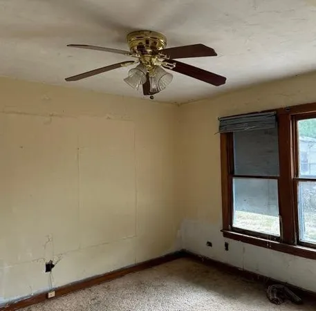 an empty room with windows and fan