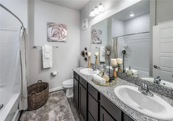 a bathroom with double vanity sinks a toilet and a mirror