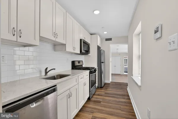 a kitchen with white cabinets and sink