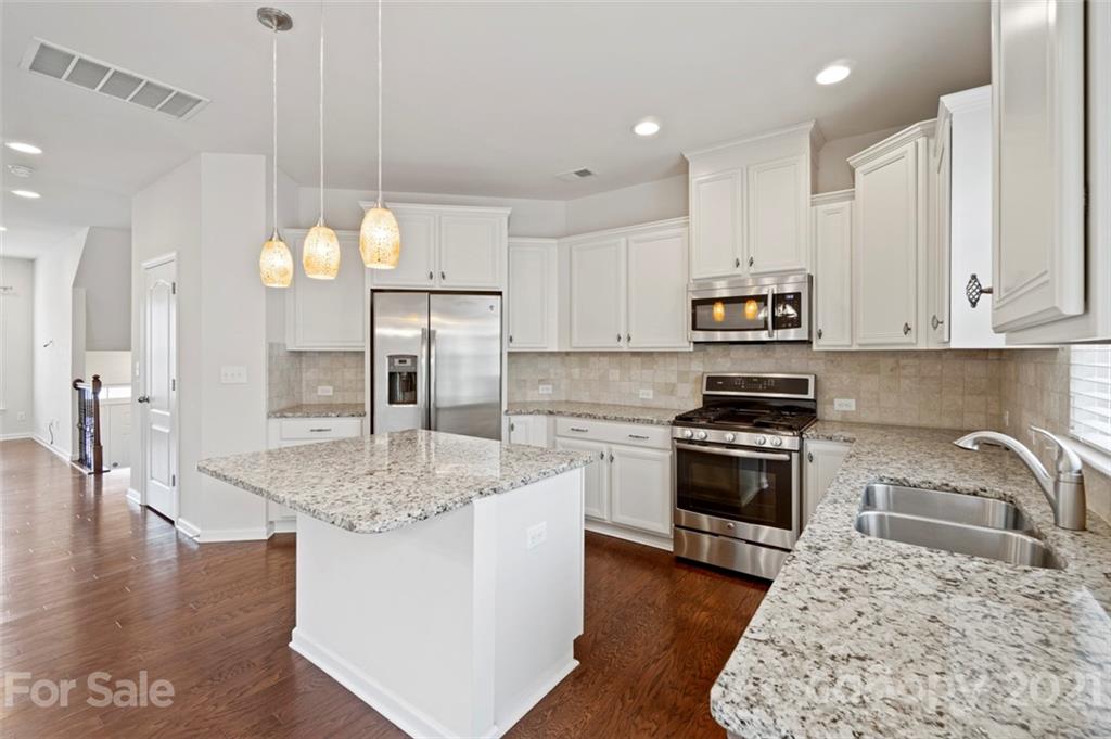 206 Butterfly Place, Unit 185 Tega Cay, SC 29708 - Photo 14 of 36 a kitchen with stainless steel appliances granite countertop a sink a stove and a wooden floors