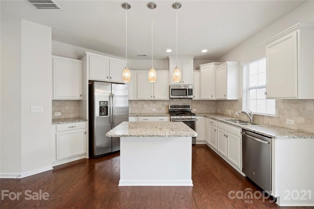 206 Butterfly Place, Unit 185 Tega Cay, SC 29708 - Photo 17 of 36 a kitchen with stainless steel appliances granite countertop a refrigerator a sink dishwasher a stove and white countertops with wooden floor