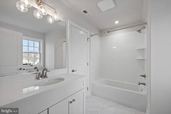 a bathroom with a tub shower sink and mirror