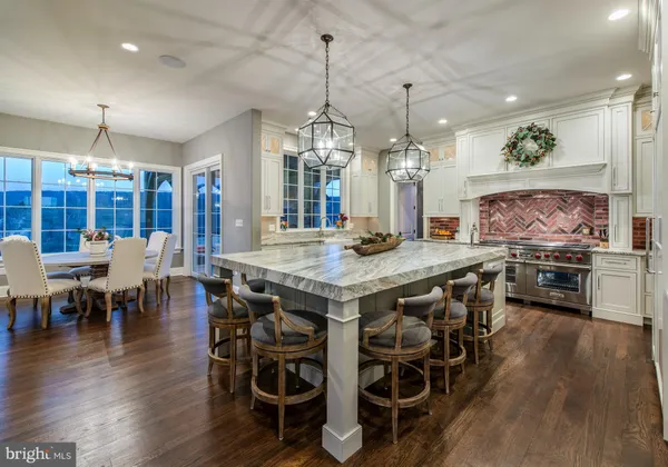an open kitchen with granite countertop a stove a sink a counter space a dining table and chairs with wooden floor