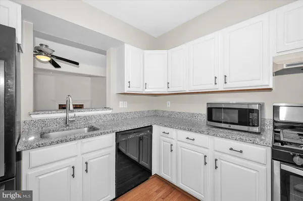 a kitchen with granite countertop white cabinets and a sink