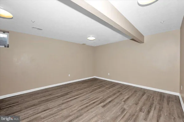 a view of an empty room with wooden floor and closet