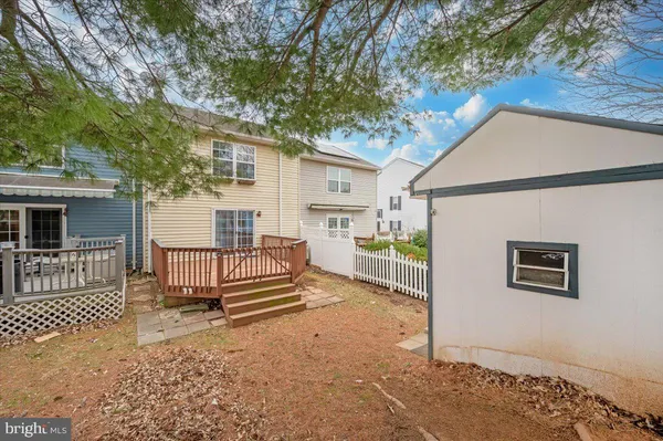 a view of a house with a wooden fence and a large tree