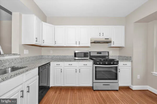 a kitchen with stainless steel appliances granite countertop a stove and white cabinets