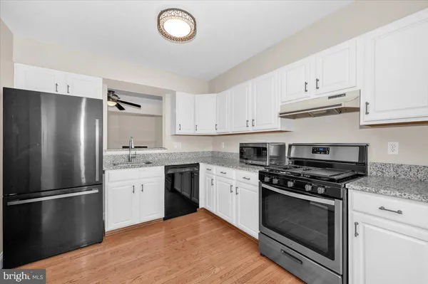 a kitchen with cabinets stainless steel appliances and wooden floor