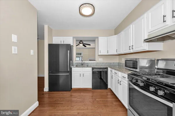 a kitchen with granite countertop a refrigerator stove and wooden cabinets