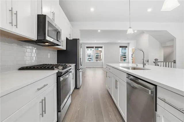 a kitchen with stainless steel appliances granite countertop a sink a stove and a wooden floors