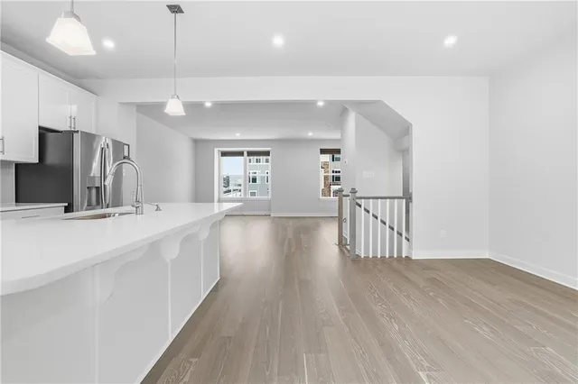 a kitchen with stainless steel appliances granite countertop a refrigerator a stove top oven a sink dishwasher and white cabinets with wooden floor