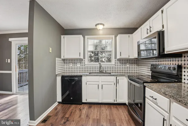 a kitchen with stainless steel appliances granite countertop a sink stove and cabinets