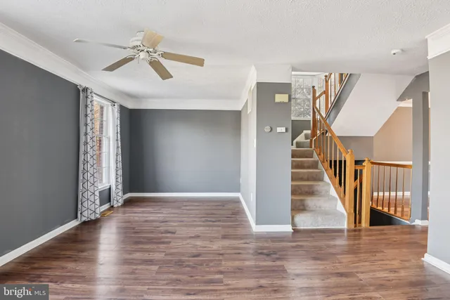 a view of an empty room with wooden floor and stairs