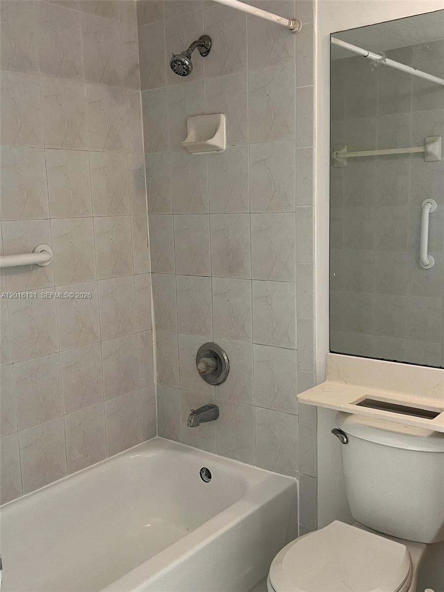12605 Southwest 91st Street, Unit 103 Miami, FL 33186 - Photo 9 of 14 a white toilet and tub sitting next to a bathroom