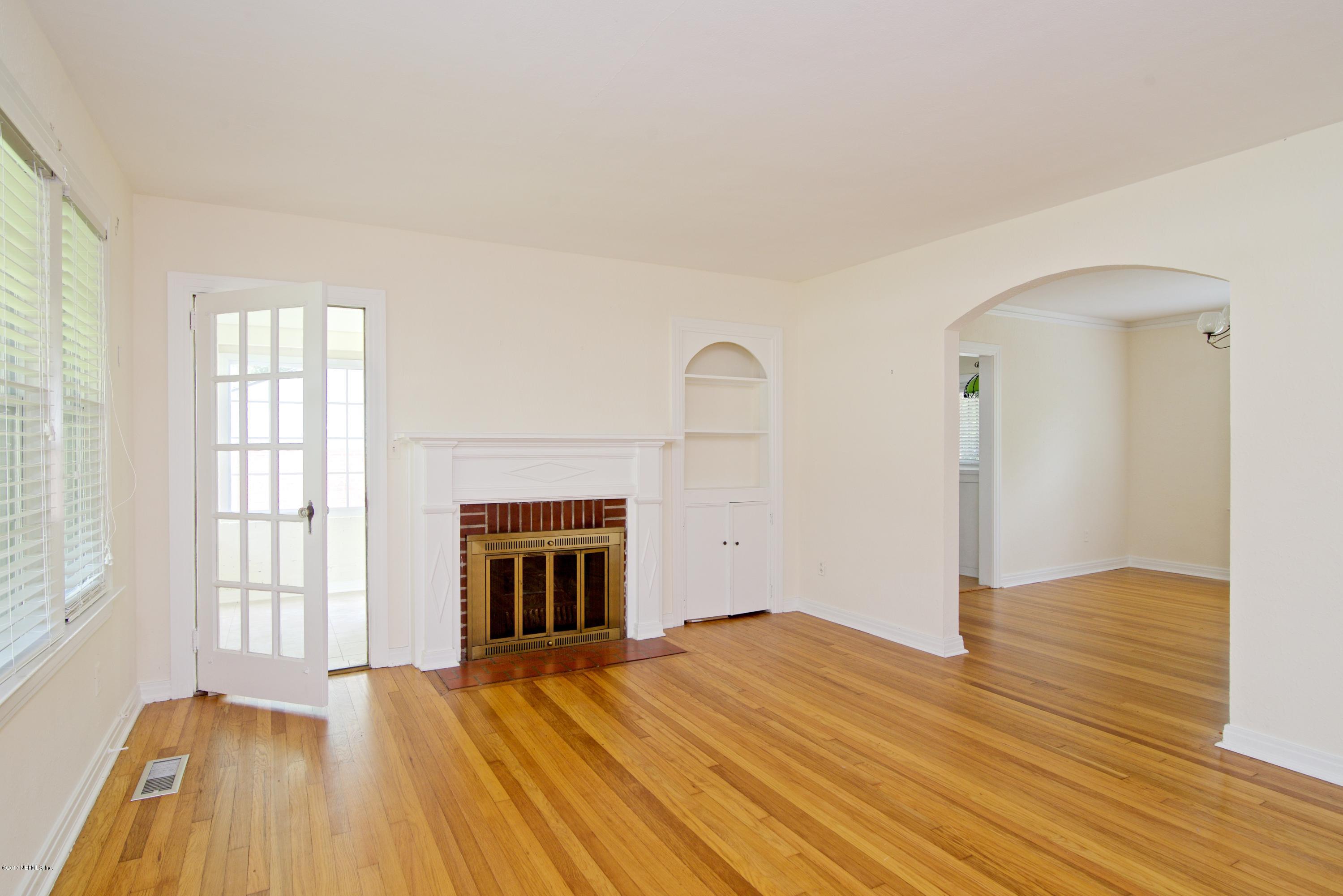 3877 Gadsden Road Jacksonville, FL 32207 - Photo 10 of 24 an empty room with wooden floor a fireplace and windows