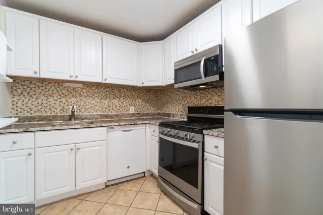 a kitchen with granite countertop white cabinets stainless steel appliances and sink