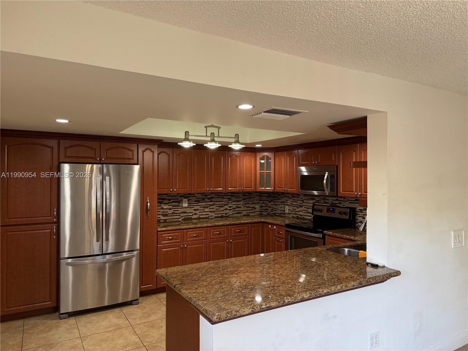 4825 Southwest 149th Court, Unit 18B Miami, FL 33185 - Photo 10 of 36 a kitchen with kitchen island a counter top space cabinets and stainless steel appliances