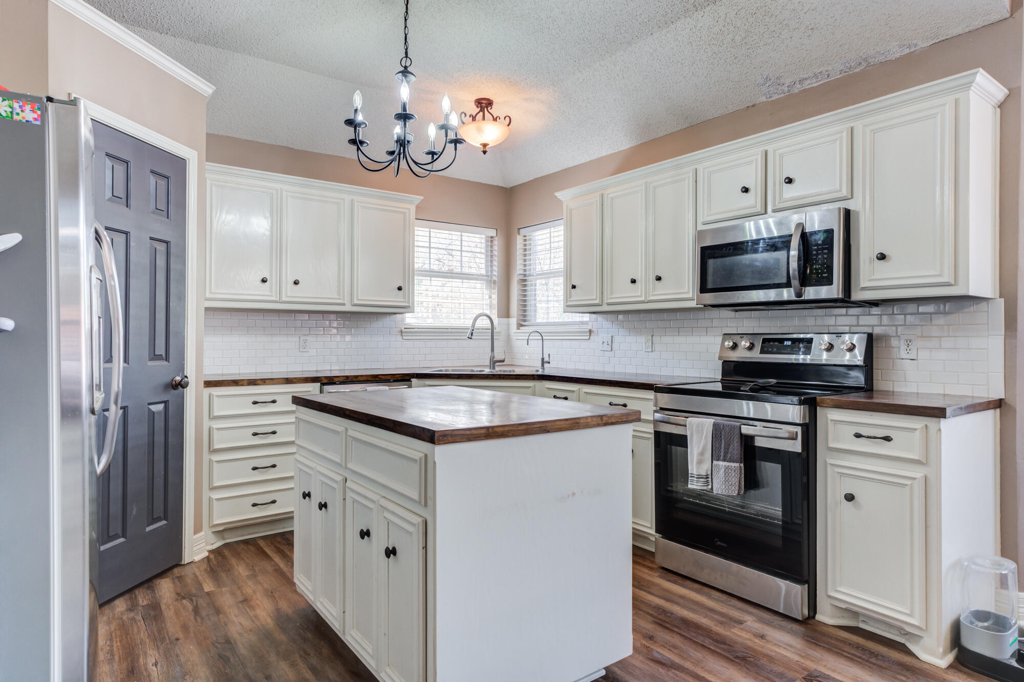 2807 87th Street Lubbock, TX 79423 - Photo 13 of 38 a kitchen with stainless steel appliances granite countertop a stove top oven a refrigerator white cabinets and wooden floor