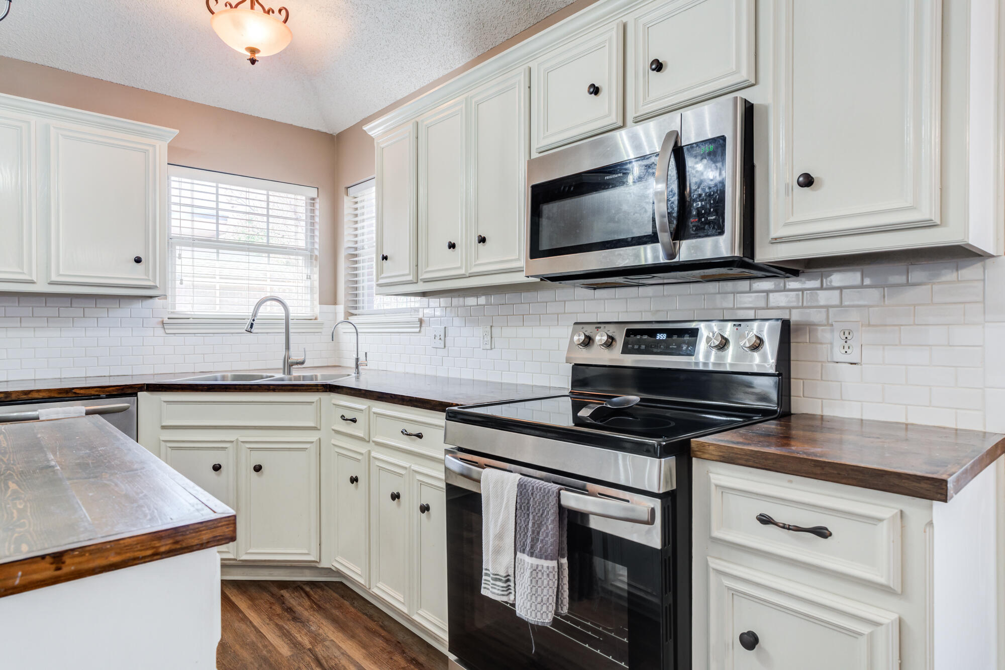 2807 87th Street Lubbock, TX 79423 - Photo 14 of 38 a kitchen with white cabinets and black appliances