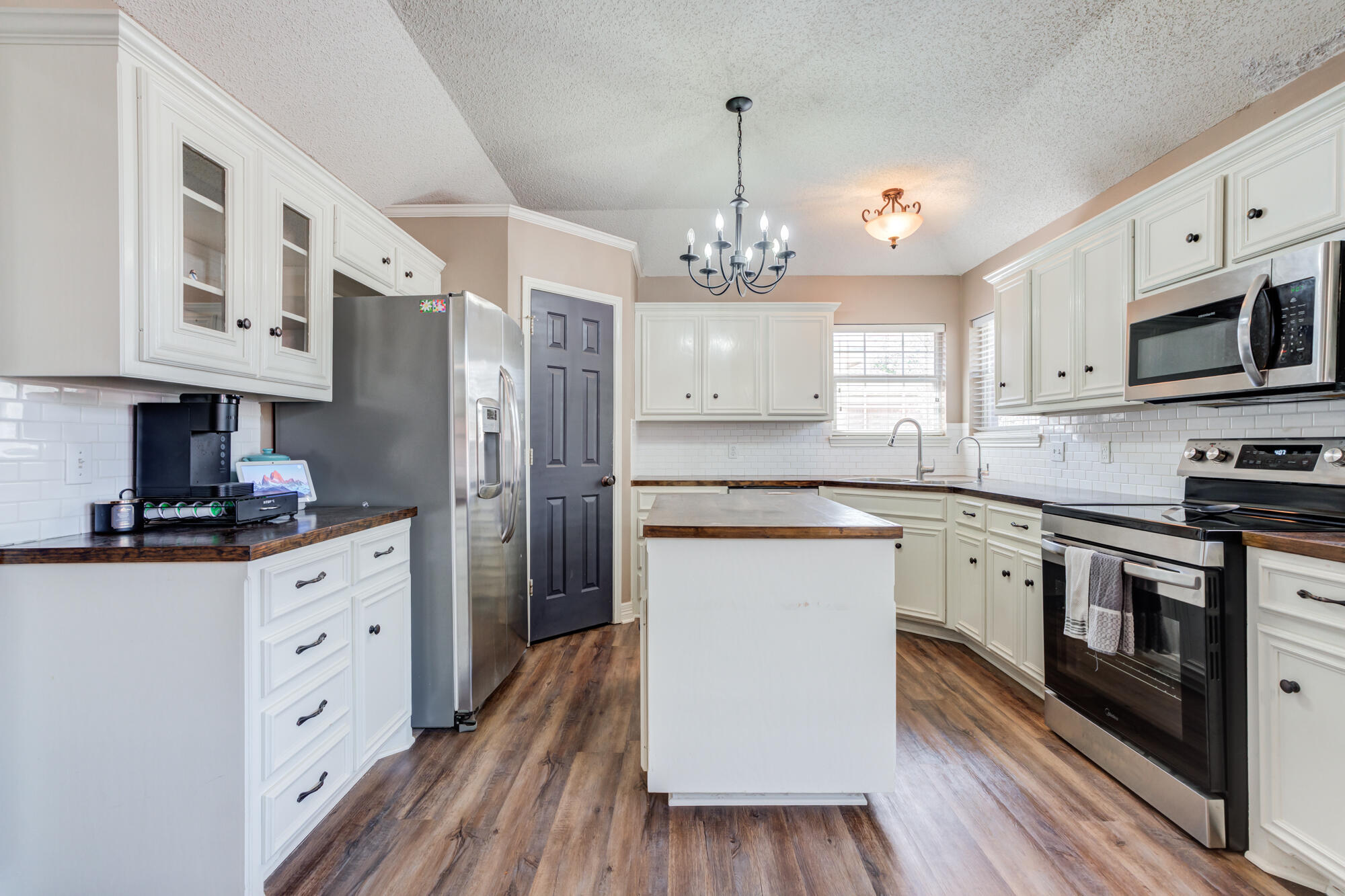 2807 87th Street Lubbock, TX 79423 - Photo 18 of 38 a kitchen with stainless steel appliances granite countertop a sink dishwasher a refrigerator and white cabinets with wooden floor
