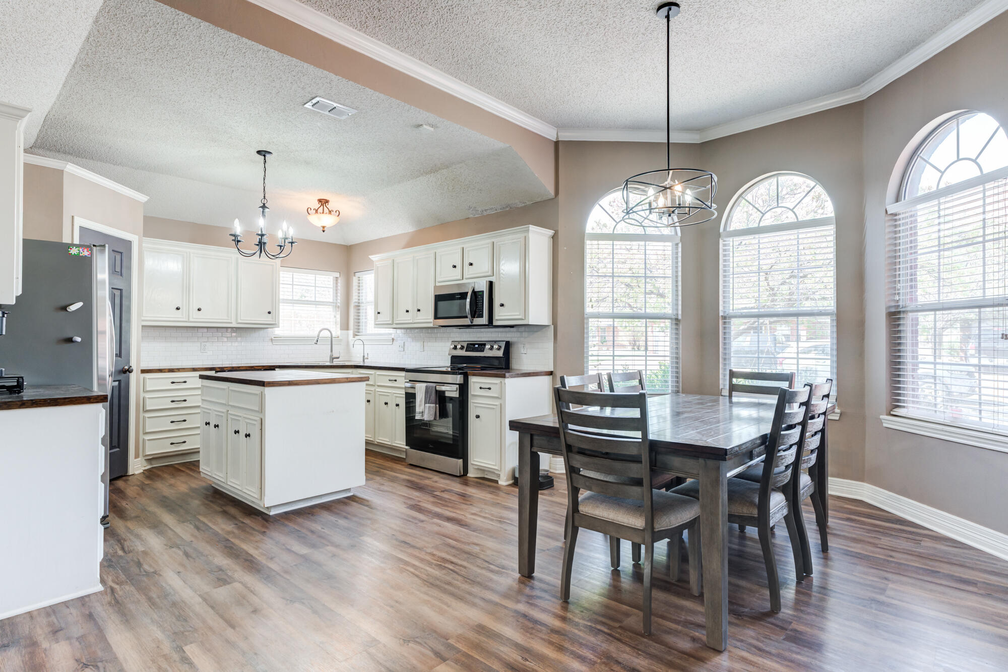 2807 87th Street Lubbock, TX 79423 - Photo 10 of 38 a kitchen with stainless steel appliances kitchen island granite countertop a dining table chairs and white cabinets