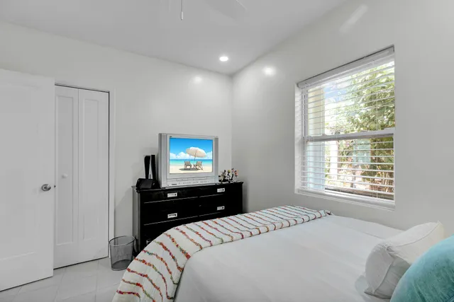 a bedroom with a bed and a flat tv screen on a dresser