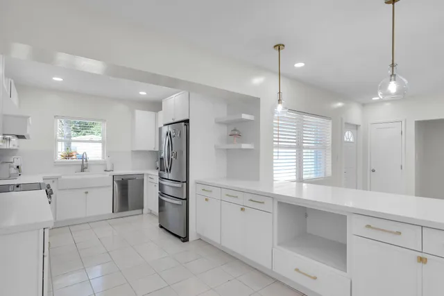 a kitchen with white cabinets and window