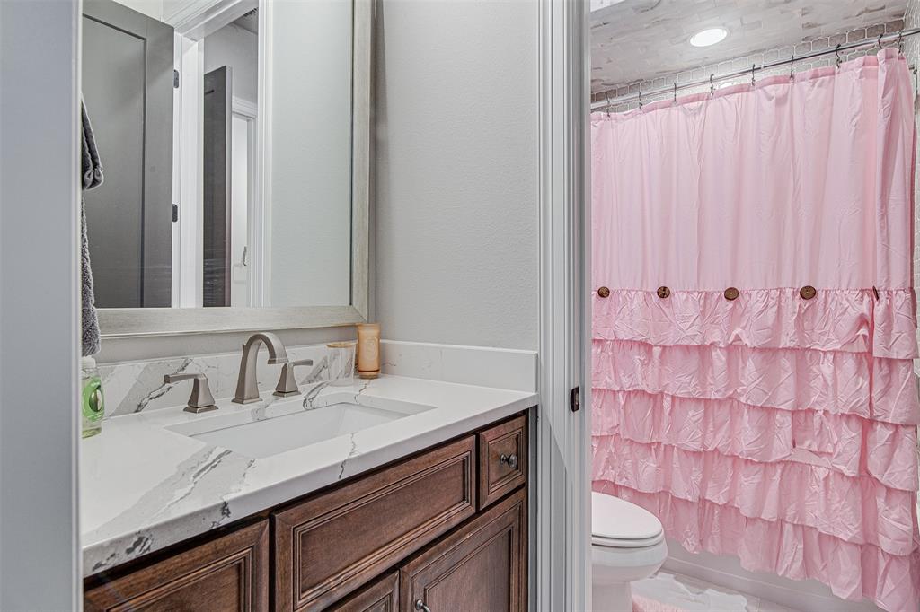 13924 East Riviera Drive Fort Worth, TX 76028 - Photo 27 of 38 a bathroom with a granite countertop sink and a mirror with toilet