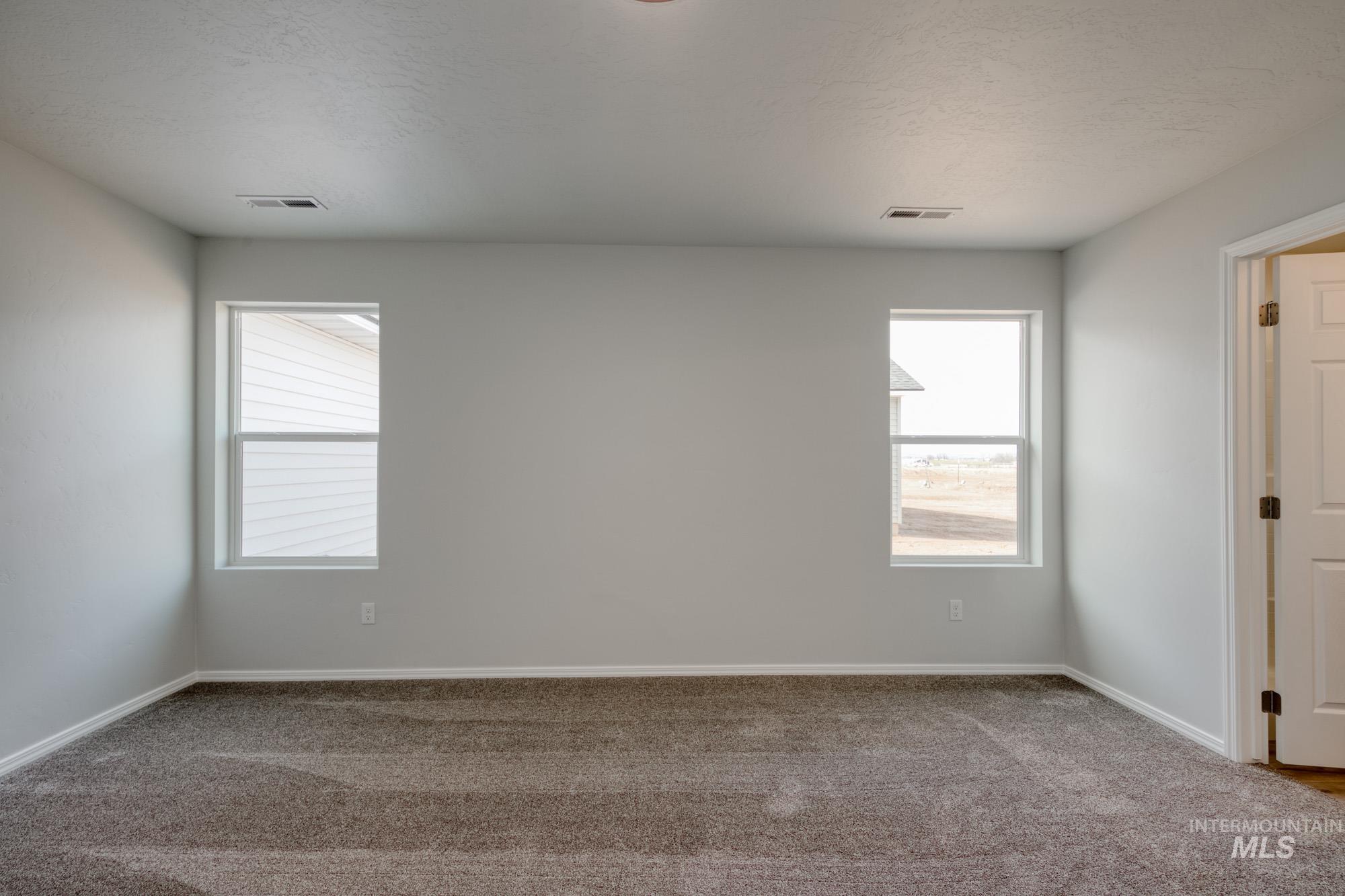 3150 South Maple Rnch Way Nampa, ID 83686 - Photo 19 of 22 Empty room featuring healthy amount of natural light, carpet, and a textured ceiling