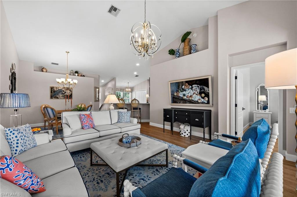 9331 Spring Run Boulevard, Unit 3005 Estero, FL 34135 - Photo 19 of 48 Vaulted ceilings with architectural ledges, gold-finish chandelier, recessed wall niche, wood-finish flooring, and open floor plan