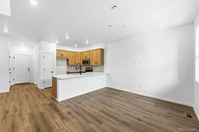 a large white kitchen with a refrigerator a stove and a wooden floor