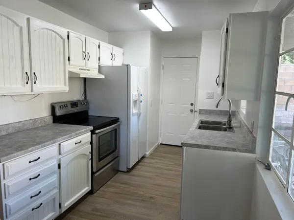 a kitchen with granite countertop white cabinets and white appliances