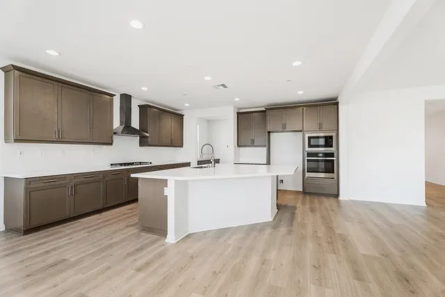 a large kitchen with stainless steel appliances a large counter top a stove and a wooden floors