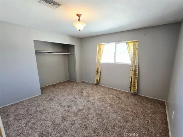 an empty room with closet and windows