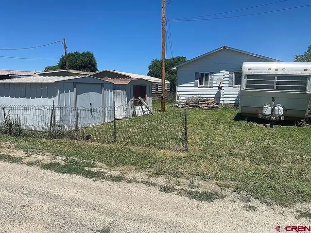 a white house that has a small yard and a table and chairs in it