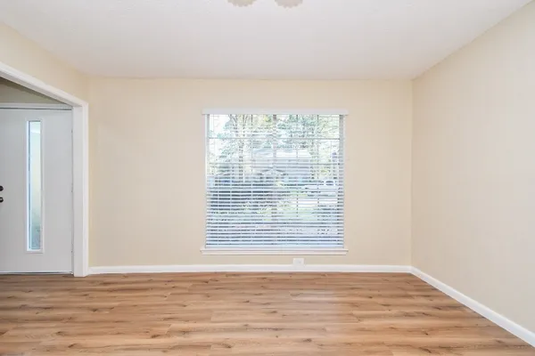 a view of an empty room with wooden floor and a window