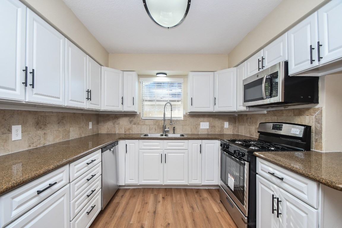 4730 Theall Road Houston, TX 77066 - Photo 9 of 32 a kitchen with stainless steel appliances granite countertop a sink a stove a microwave and cabinets