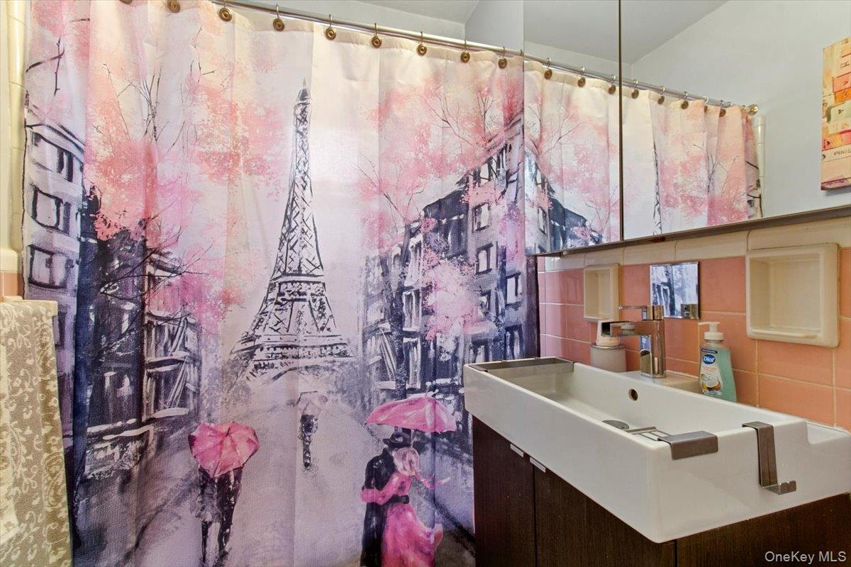 103 Wiltshire Road, Unit D11 Scarsdale, NY 10583 - Photo 15 of 23 a bathroom with a sink and mirror with bathtub