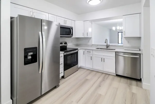 a kitchen with stainless steel appliances granite countertop a refrigerator a stove top oven a sink and dishwasher