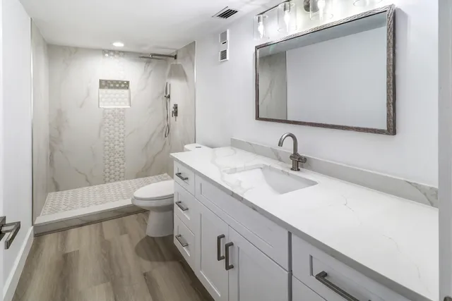 a bathroom with a sink a toilet and shower