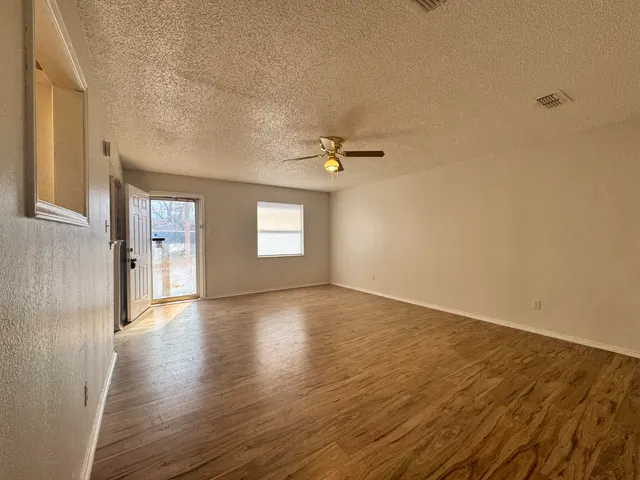 a view of an empty room with a window and wooden floor