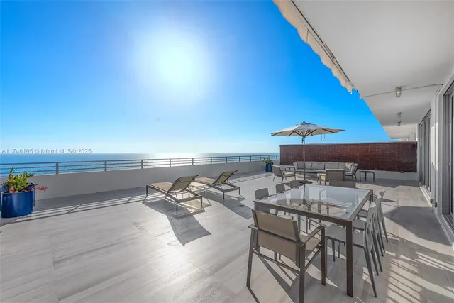 a view of a patio with couches table and chairs under an umbrella