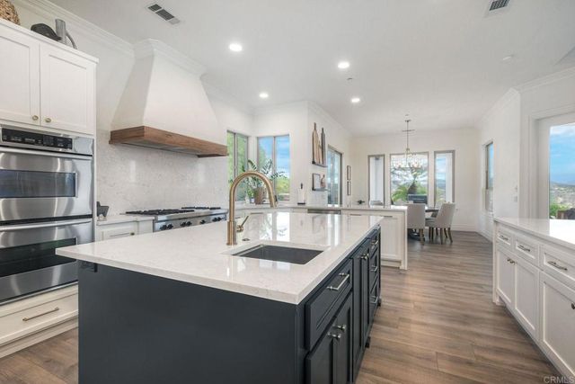 a kitchen with stainless steel appliances kitchen island a refrigerator a stove a sink and a dining table with wooden floor