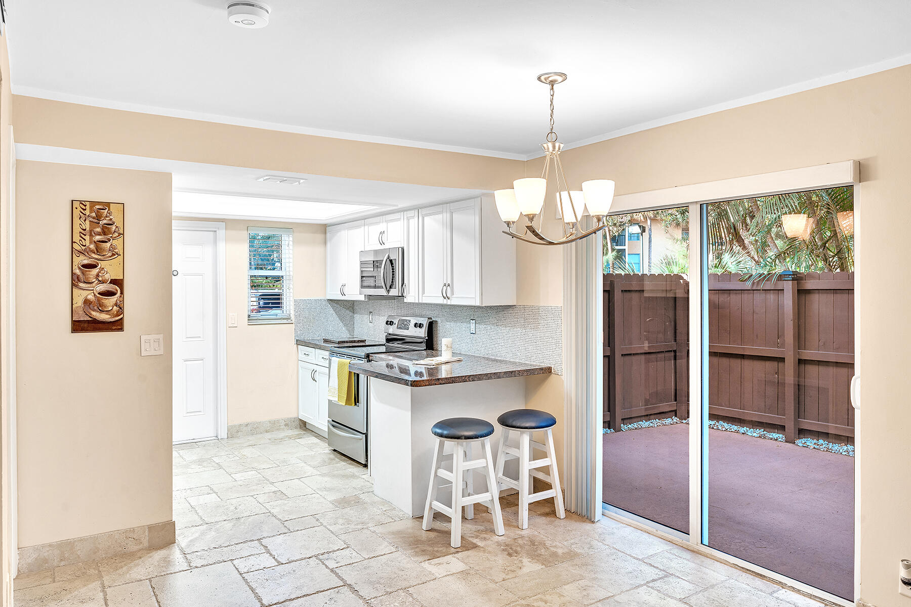 1945 Northwest 4th Avenue, Unit 32C Boca Raton, FL 33432 - Photo 17 of 52 a kitchen with kitchen island granite countertop a stove a refrigerator a sink a dining table and chairs with wooden floor