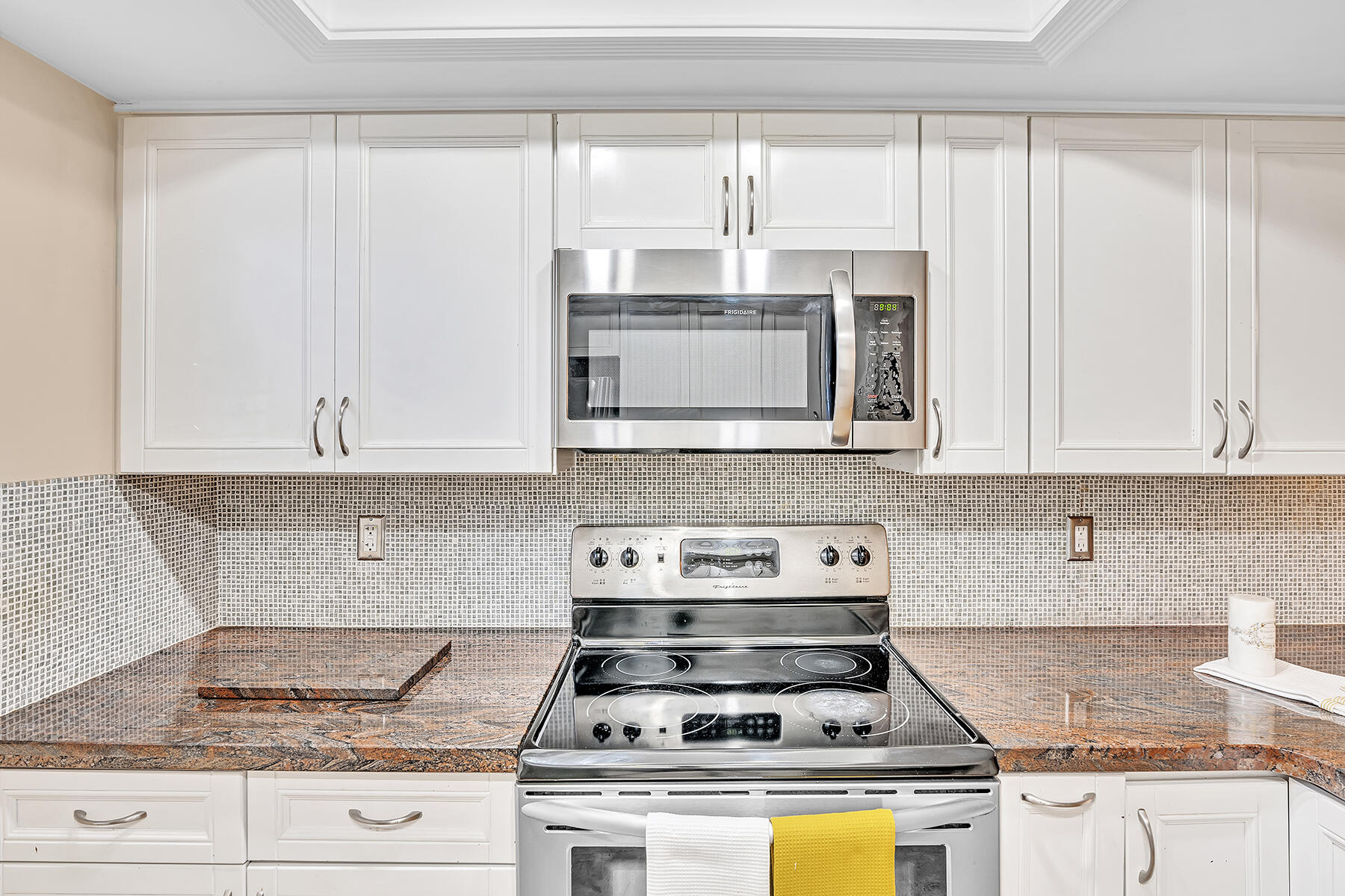 1945 Northwest 4th Avenue, Unit 32C Boca Raton, FL 33432 - Photo 25 of 52 a kitchen with granite countertop a stove a sink and white cabinets
